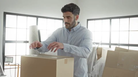 Man rests hands on a cardboard box while packing and moving in studio amid .. Stock Footage 337373581