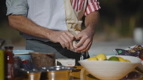 Man retrieve garlic bulbs from a pack standing behind a kitchen shelf Stock Footage 247054659