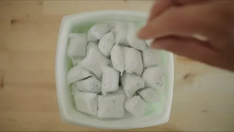 Man retrieves Dish Detergent Laundry soap pod packet to do chores in kitchen Stock Footage 161804077