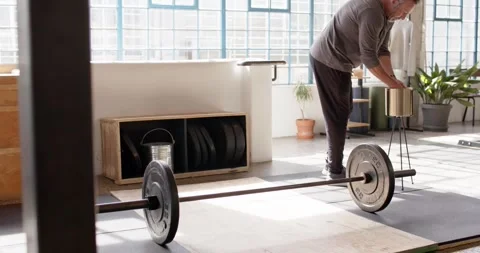 Man retrieving chalk, stepping to loaded barbell in loft studio wearing workout Stock Footage 337289288