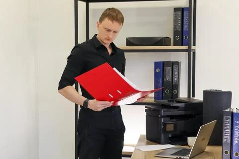 Man reviewing documents in red folder at office desk Stockfoto's