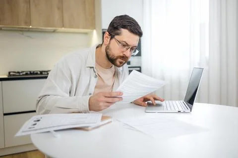 Man reviewing important documents and looking at papers and laptop during wor Foto stock