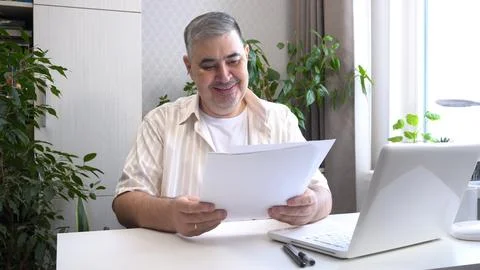 Man Reviewing Work Documents and Smiling Fotos de archivo