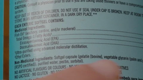 Man reviews omega 3 supplement packaging for nutritional content and benefits Stock Footage 303560341