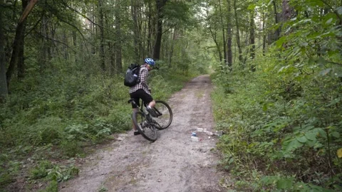 Man ride bicycle through forest, collecting trash. Trendy sports programs Stock Footage 139844193