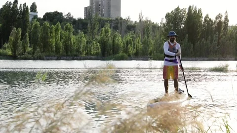Man ride on SUP board in the mountain lake in city Stock Footage 204087508