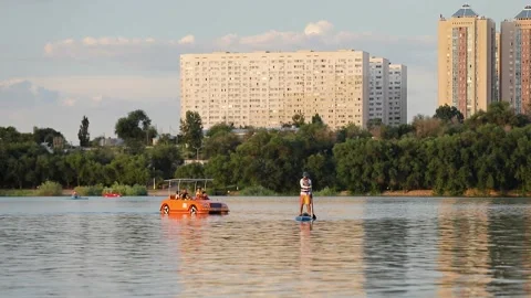 Man ride on SUP board in the mountain lake in city Stock Footage 204087614