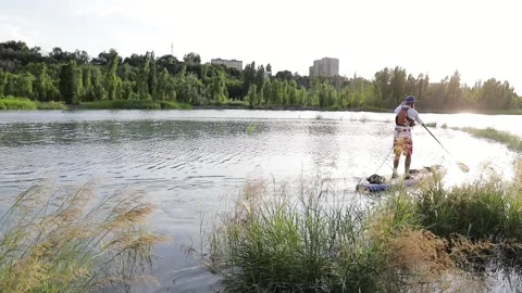 Man ride on SUP board in the mountain lake in city Stock Footage 204087771