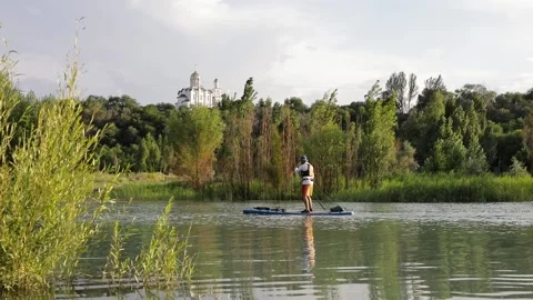 Man ride on SUP board in the mountain lake in city Stock Footage 204088074