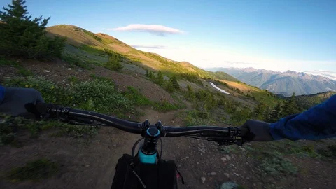 Man Rides Alpine Trail At Sunset With Views Of Mountains And Flowers Stock Footage 115103535