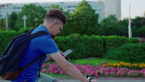Man rides a bicycle and uses a smartphone Stock Footage 79071837