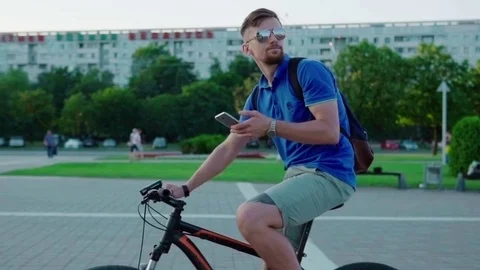 Man rides a bicycle and uses a smartphone Stock Footage 79071968