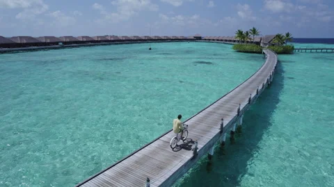 A man rides a bicycle on a beach in the Maldives Stock Footage 243296676