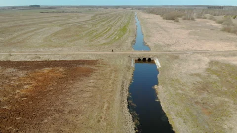 A man rides a Bicycle over a bridge over a narrow river, on a gravel road Vídeo Stock 106928218