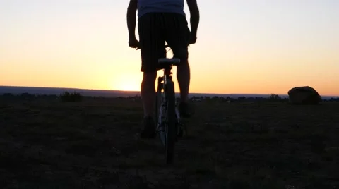Man rides bicycle into sunset. Stock Footage 54515126
