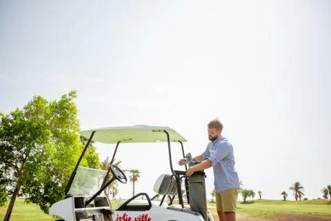 A man rides a golf course on a golf cart Stock Photos