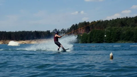 A Man Rides His Wakeboard At A Cable Park, Slow Motion. wake boarding tricks. Video stock 97041307