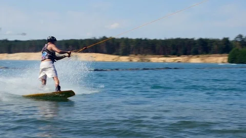 A Man Rides His Wakeboard At A Cable Park, Slow Motion. wake boarding tricks. Video stock 97063607