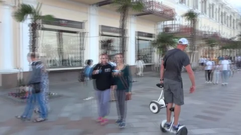 A man rides a hoverboard in the park and maneuvers between people Stock Footage 168886239