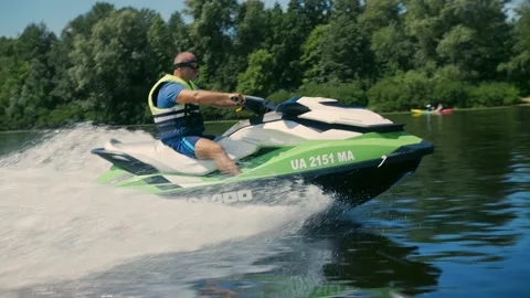 Man rides a jet ski against a background of the city and green leaves. A bea Stock Footage 201518318