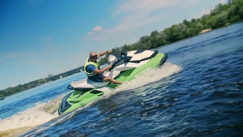 Man rides a jet ski against a background of the city and green leaves. Beaut Stock Footage 201518448