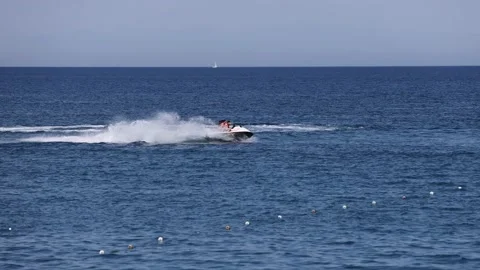 A man rides a jet ski at high speed on the blue sea on a warm summer day, slow Stock Footage 203878732