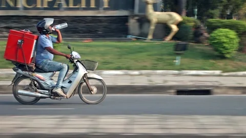 A man rides a motorcycle and drinks water from a plastic bottle Stock Footage 270280822