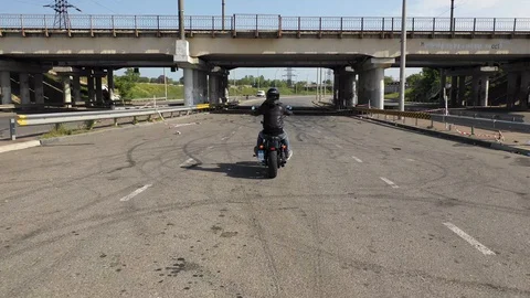 Man rides a motorcycle under a bridge Stock Footage 129105019