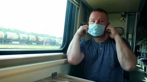 A man rides a train by the window. He takes off his medical mask Stock Footage 156540956