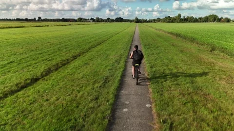 Man Riding Bicycle Along Fields — Drone 4K 動画素材 317847337