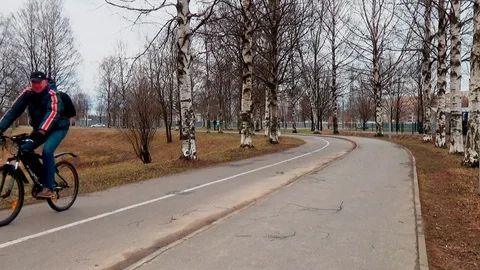 A man is riding a bicycle along the path of the city park Stock Footage 75203870