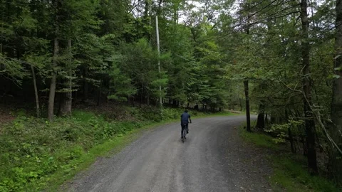 Man riding bicycle down hill filmed from behind footage from back casual clothes Stock Footage 251659459