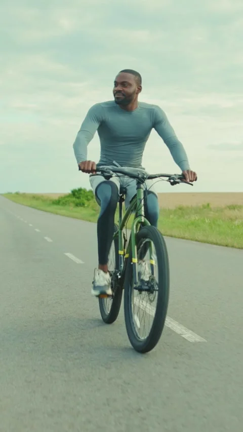 A man is riding a bicycle down a long and winding road ahead Stock Footage 301829954
