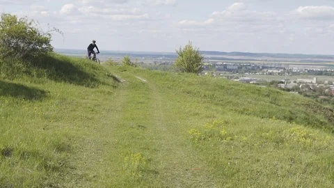 Man Riding Bicycle up Mountain Grass Hill 動画素材 75562255