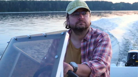 A man riding a boat on the river on a summer evening against the background of a Vídeo Stock 283530302