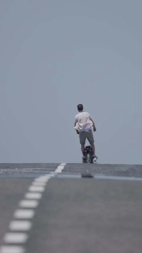Man riding electric unicycle on empty road Stock Footage 310698175