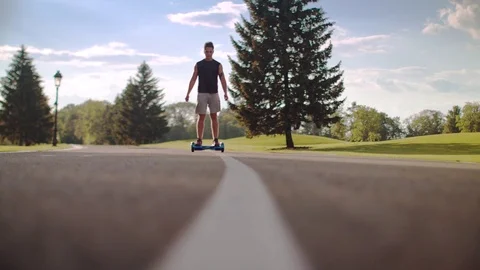 Man riding on hoverboard at park road. Man driving two wheel electric skateboard Stockbeeldmateriaal 73530927