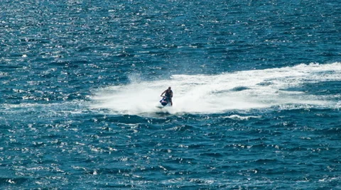Man Riding Jet Ski Speeding on Blue Ocean Water with White Splashes Stock-Footage 61006913