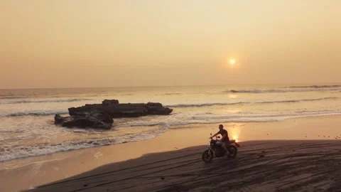 Man riding motorcycle on beach during sunset Stockbeeldmateriaal 340847400