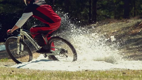 Man riding mtb down the hill in a patch of snow in super slow motion Stock Footage 146860147
