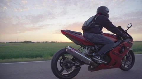 Man riding red motorcycle during sunset Stock Footage 146653334
