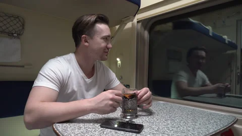 Man is riding in a train, sitting at a table and looking out the window Stock-Footage 263471679
