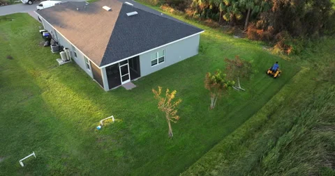 Man riding zero turn lawn mower cutting grass in summer at Florida house yard. Video stock 305374699