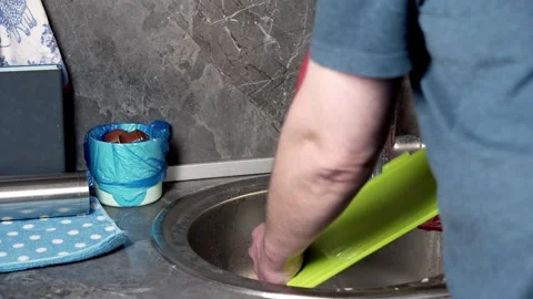 The man rinses the green plastic cutting board to remove the soap. Stock Footage 251852553