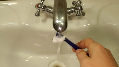 Man rinses shaving machine after shaving Stock Footage 82281095