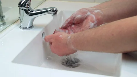 Man rinsing soap from hands under faucet after washing hands Stock Footage 129051338