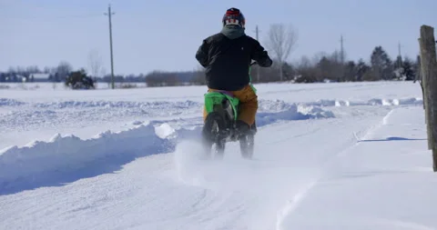 Man rips fast down snowy path with dirt bike - from behind Stock Footage 148225826