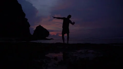 Man rising hands, posing like athlete, having fun at sunrise above ocean. Video stock 84843739