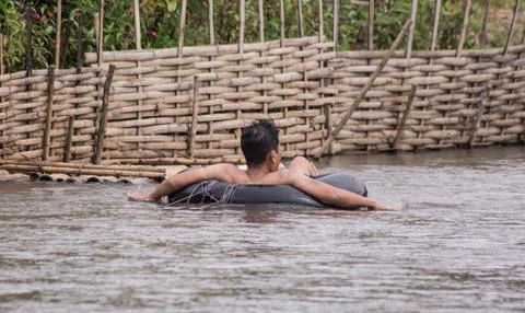 A man in a river sitting in a rubber ring. Stock Photos