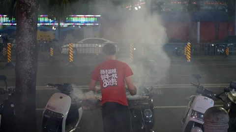 Man roasting meat cubes by street, lots of smoke, Zhanjiang, China Stock Footage 334099086